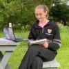A student reading a book at a picnic table.