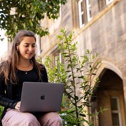 A woman with ear buds in watching a webinar on her laptop