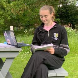 A student reading a book at a picnic table.