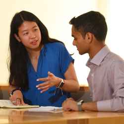 Pembroke College Teacher & Adviser Session Image of a student and teacher. Teacher is explaining something to the student whilst pointing at a book