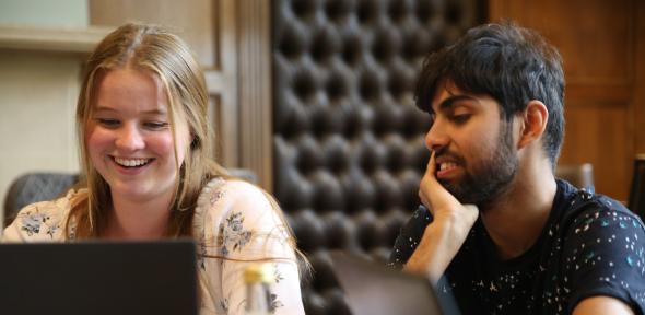 Two smiling students looking at a laptop
