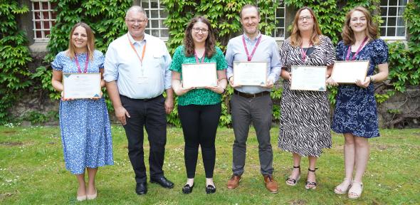 A number of educators holding up their awards, smiling