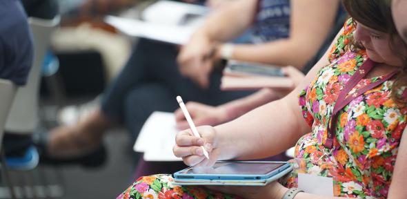 Sitting female holding their tablet/laptop and a pen