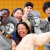 Group of young people hanging out with ancient statues on an orange background