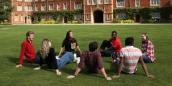 A photo of Jesus College with students sitting on the grass