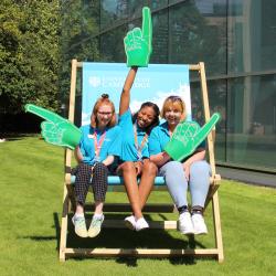 Three students in an oversize deckchair with foam hands