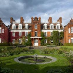 Image of Newnham College's Sidgwick building. Red-brick building stands before a grassy sunken garden. 