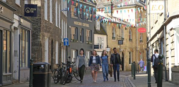 Students walking down the cobbled Green Street with colourful bunting hung between the buildings. 