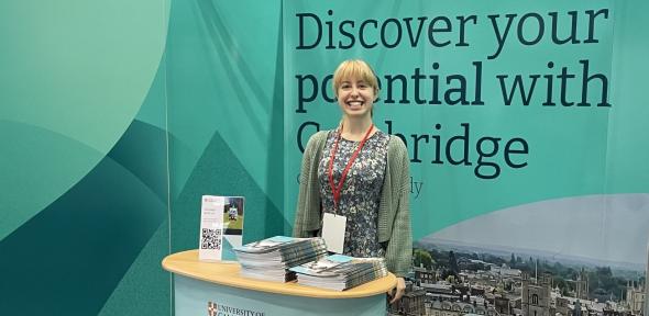 Smiling representative at the University of Cambridge stand
