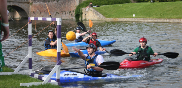 King's College students playing kayak polo, where a team member is about to score into their opponent's goal